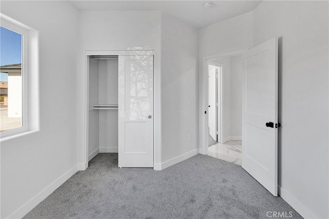 unfurnished bedroom with light carpet and a closet