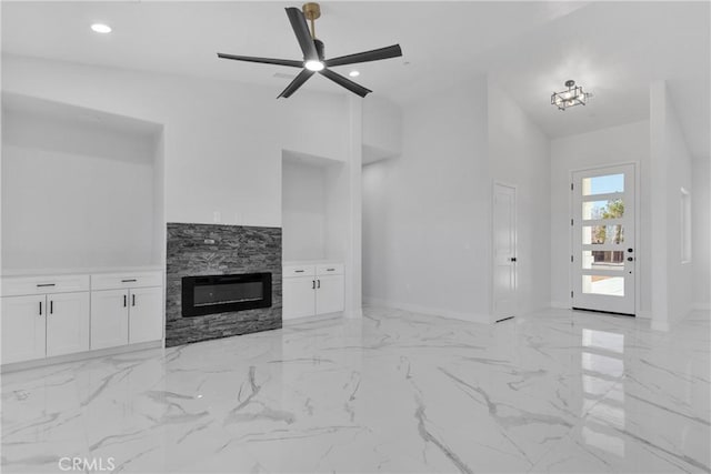 unfurnished living room with ceiling fan, a fireplace, and high vaulted ceiling