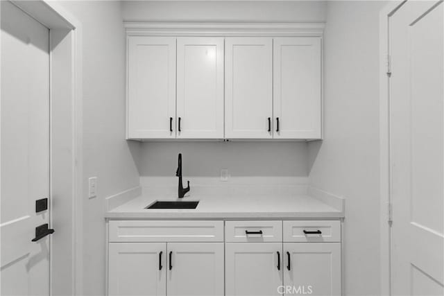 bar with white cabinets and sink