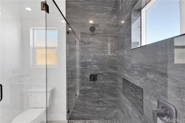 bathroom with a shower with shower door and toilet