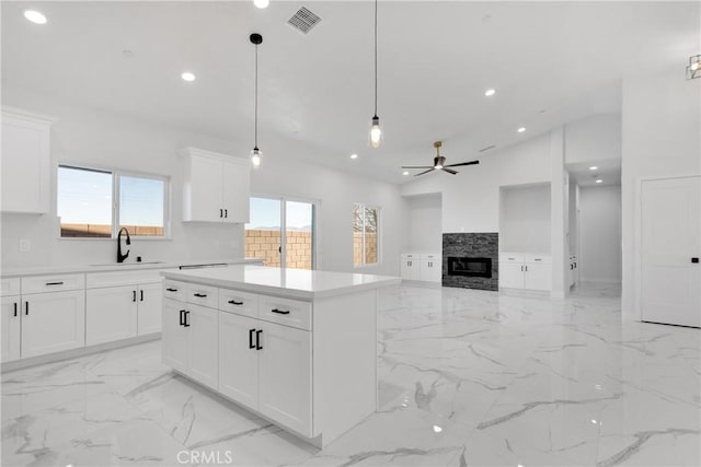 kitchen with ceiling fan, vaulted ceiling, pendant lighting, white cabinets, and sink