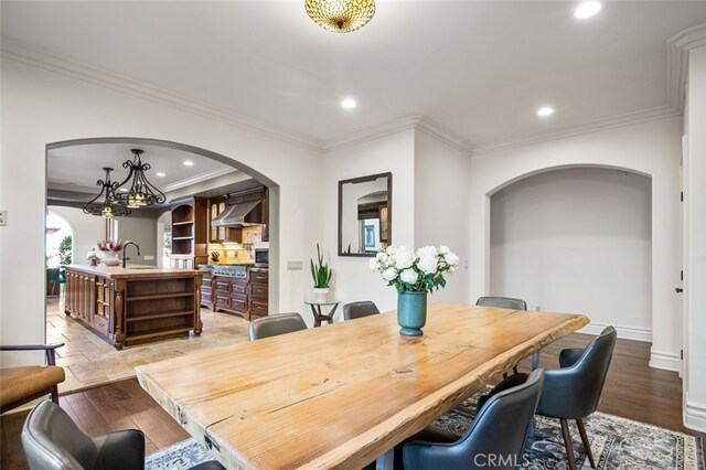 dining space with sink, ornamental molding, and light wood-type flooring