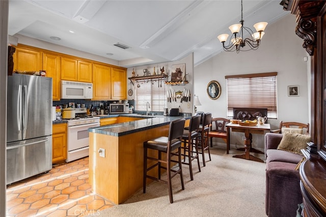 kitchen featuring appliances with stainless steel finishes, an inviting chandelier, decorative backsplash, kitchen peninsula, and a breakfast bar