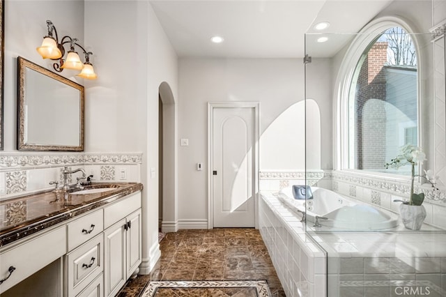 bathroom featuring tiled bath and vanity