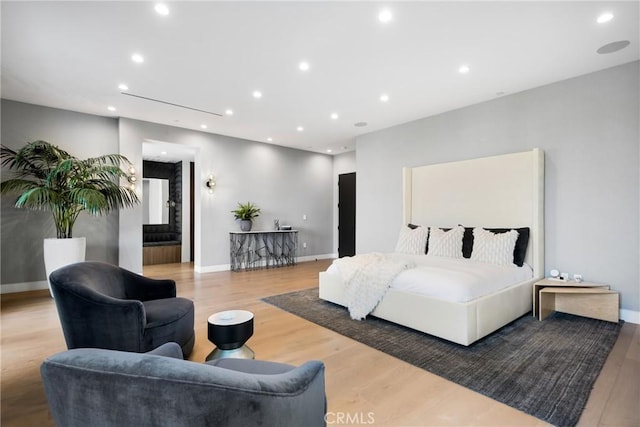 bedroom with hardwood / wood-style floors and ensuite bath