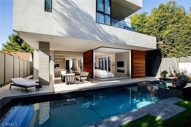 rear view of property featuring a fenced in pool, an outdoor living space with a fireplace, a balcony, and a patio