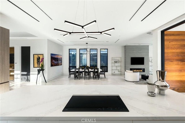 interior space with an inviting chandelier, a healthy amount of sunlight, a fireplace, pendant lighting, and light stone counters