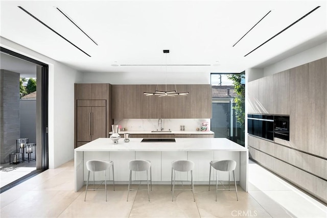 kitchen featuring decorative light fixtures, a healthy amount of sunlight, a breakfast bar area, a wall of windows, and paneled refrigerator