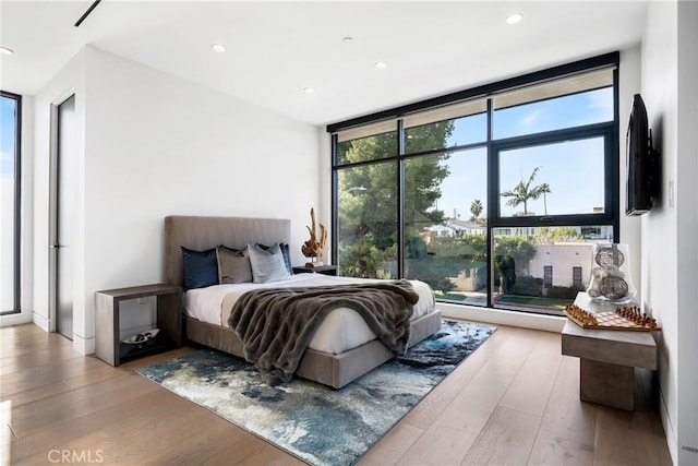 bedroom featuring a wall of windows and light hardwood / wood-style flooring