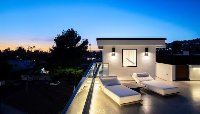 patio terrace at dusk featuring a balcony