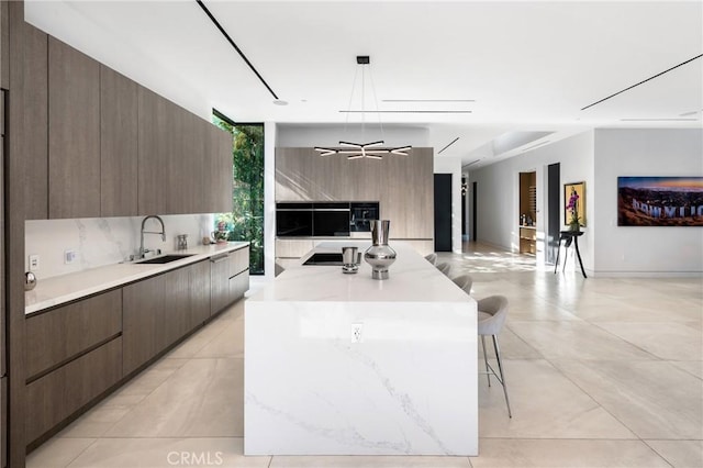 kitchen featuring decorative light fixtures, a spacious island, a breakfast bar, sink, and a wall of windows