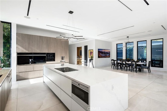 kitchen featuring a large island, a notable chandelier, black electric stovetop, and pendant lighting