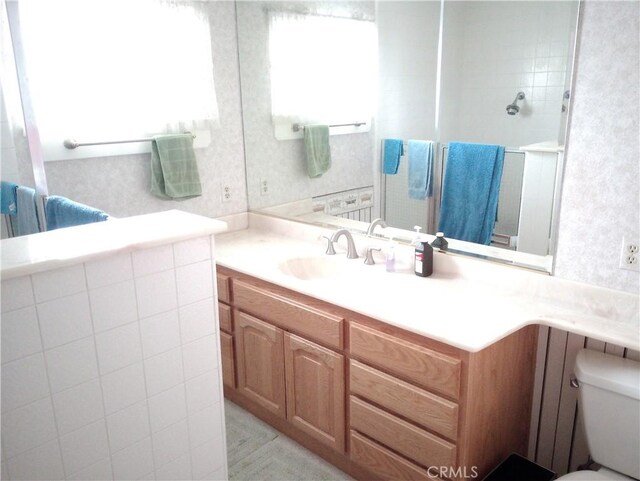 bathroom with toilet, vanity, and a shower with shower door