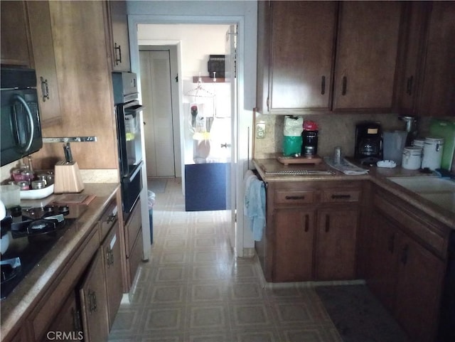 kitchen featuring black appliances, tile counters, sink, and tasteful backsplash