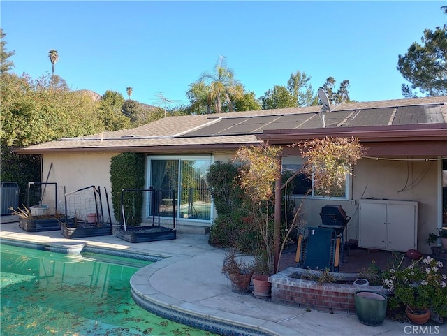 back of property featuring a fenced in pool, cooling unit, solar panels, and a patio