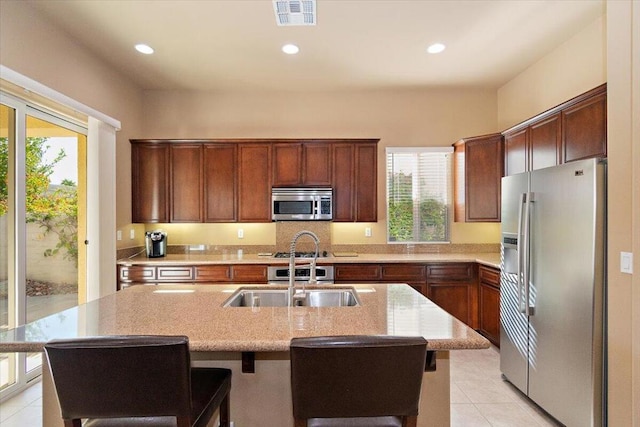 kitchen featuring a kitchen breakfast bar, a kitchen island with sink, sink, and stainless steel appliances