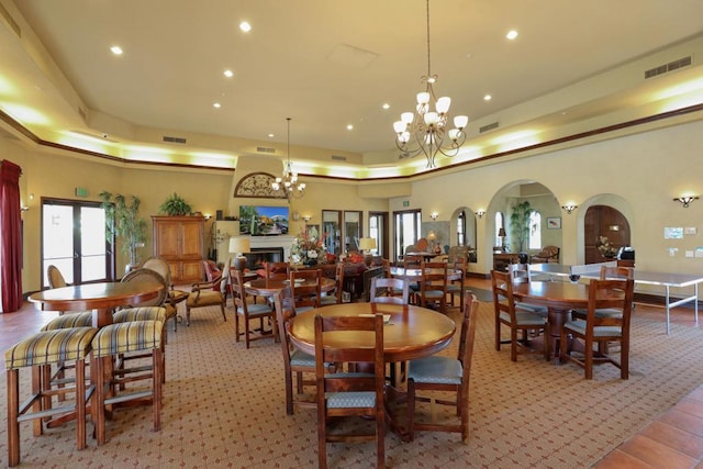 carpeted dining space featuring a towering ceiling, a tray ceiling, and a notable chandelier