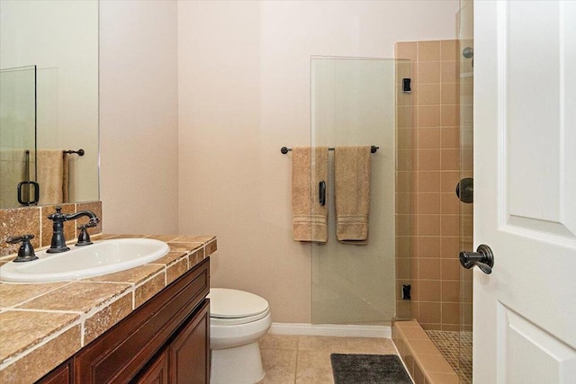 bathroom featuring toilet, vanity, tile patterned flooring, and a shower with door