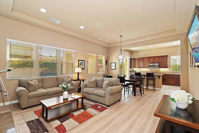 living room featuring a raised ceiling and light hardwood / wood-style floors