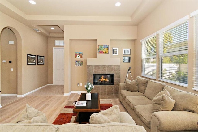 living room with hardwood / wood-style floors, a raised ceiling, and a fireplace