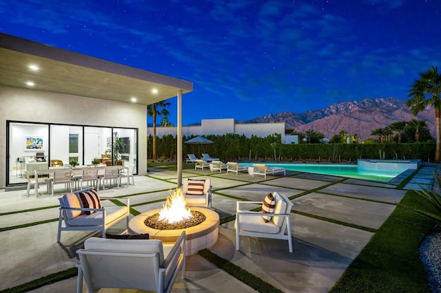 view of patio with a fenced in pool, a fire pit, and a mountain view