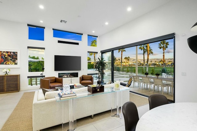 living room with light tile patterned flooring, plenty of natural light, and a high ceiling