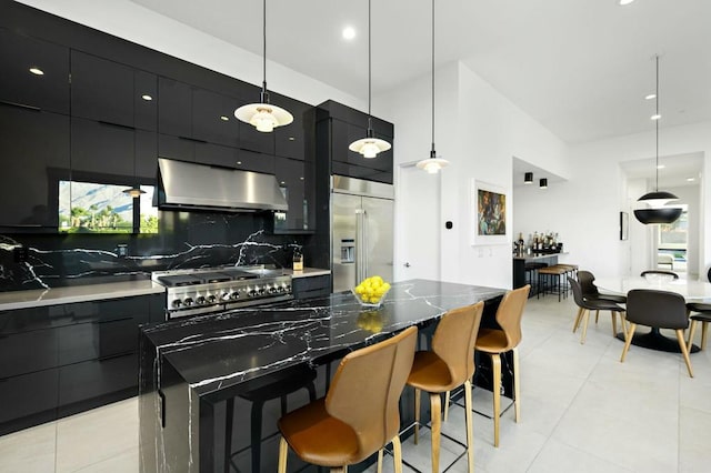 kitchen featuring a spacious island, hanging light fixtures, stainless steel appliances, range hood, and decorative backsplash