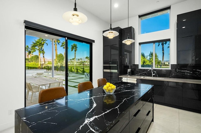 kitchen featuring decorative light fixtures, tasteful backsplash, sink, dark stone countertops, and a spacious island