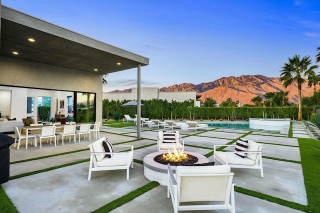 view of patio / terrace featuring a fenced in pool, an outdoor fire pit, and a mountain view