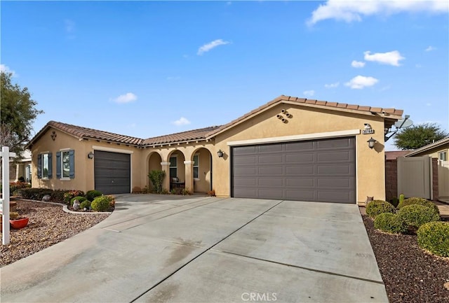 mediterranean / spanish-style house with a garage, driveway, and stucco siding