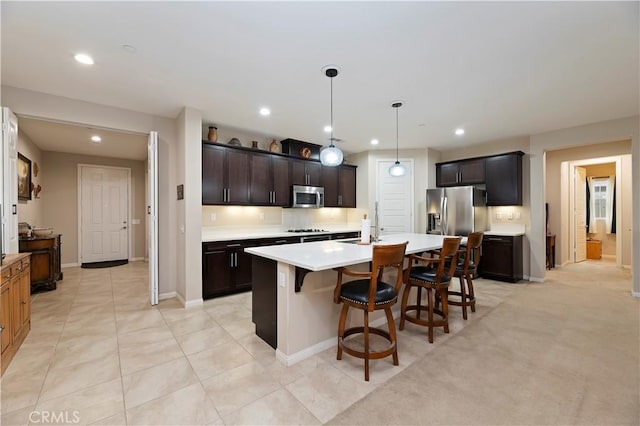 kitchen featuring recessed lighting, stainless steel appliances, a breakfast bar, light countertops, and a center island with sink