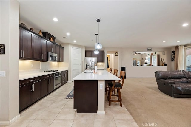 kitchen with a kitchen breakfast bar, open floor plan, light countertops, appliances with stainless steel finishes, and dark brown cabinets