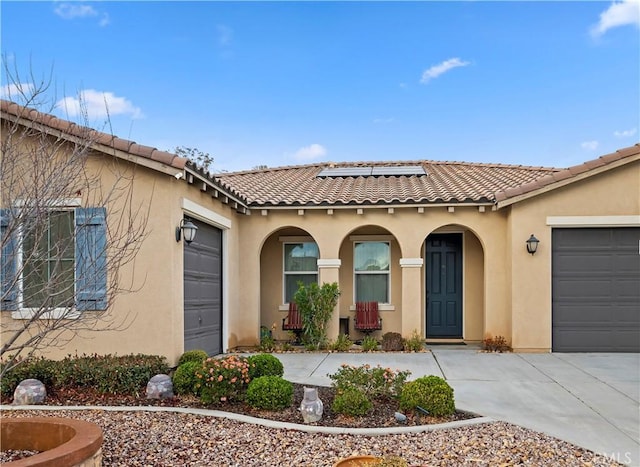 view of front of home with solar panels, driveway, an attached garage, and stucco siding