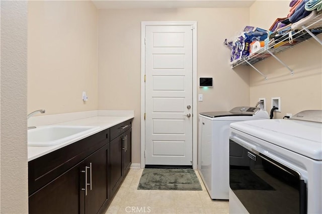 washroom featuring light tile patterned floors, separate washer and dryer, a sink, and cabinet space