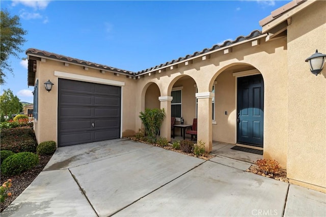 exterior space featuring a garage, driveway, a porch, and stucco siding