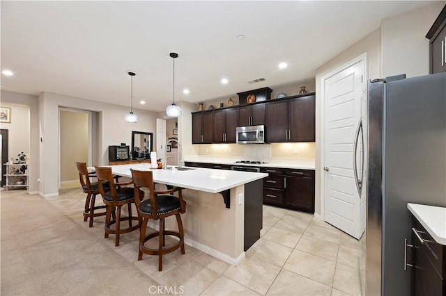 kitchen featuring a breakfast bar, stainless steel appliances, recessed lighting, visible vents, and light countertops