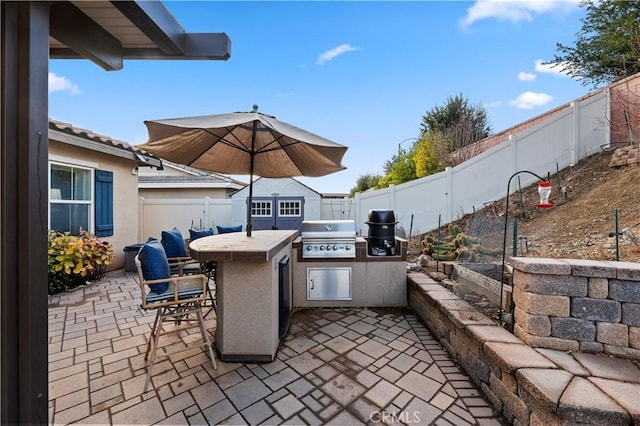 view of patio featuring exterior kitchen, a fenced backyard, outdoor dry bar, and area for grilling