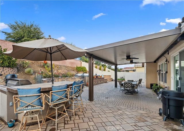 view of patio with an outdoor kitchen, ceiling fan, a fenced backyard, outdoor dry bar, and outdoor dining space