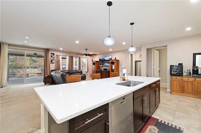 kitchen with a sink, a kitchen island with sink, light countertops, and stainless steel dishwasher