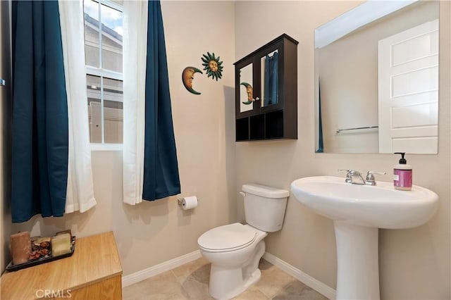 bathroom with baseboards, a sink, toilet, and tile patterned floors