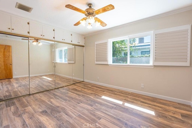 unfurnished bedroom with ornamental molding, light hardwood / wood-style floors, ceiling fan, and a closet