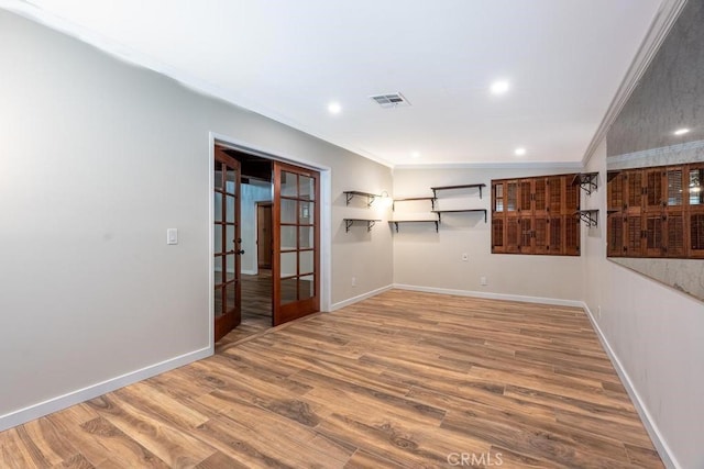 empty room featuring hardwood / wood-style floors, crown molding, vaulted ceiling, and french doors