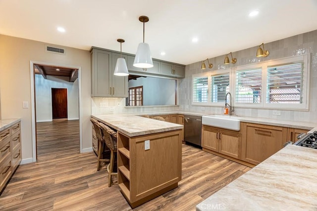 kitchen featuring sink, kitchen peninsula, dishwasher, pendant lighting, and hardwood / wood-style floors