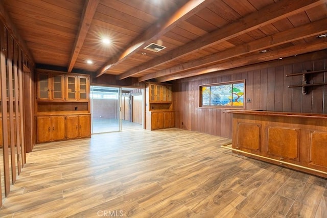 interior space with beamed ceiling, a healthy amount of sunlight, wooden ceiling, and wood walls