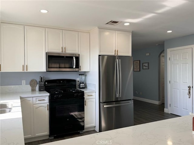 kitchen featuring dark wood-type flooring, white cabinets, appliances with stainless steel finishes, and light stone countertops