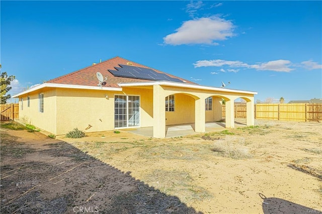 rear view of house with solar panels and a patio