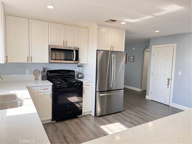 kitchen with sink, white cabinetry, appliances with stainless steel finishes, and hardwood / wood-style floors