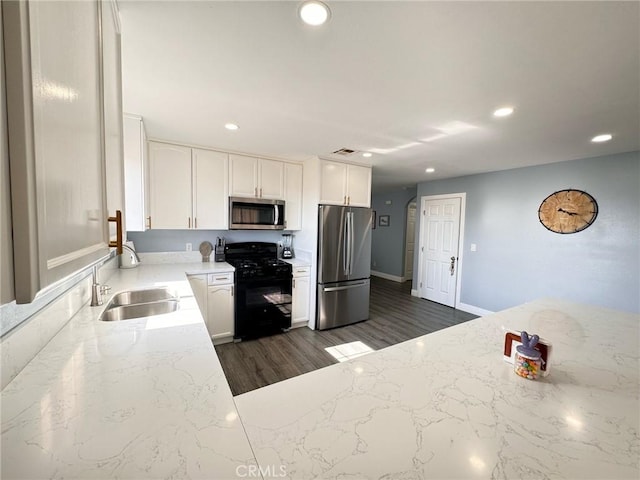 kitchen with stainless steel appliances, dark hardwood / wood-style floors, light stone countertops, white cabinets, and sink