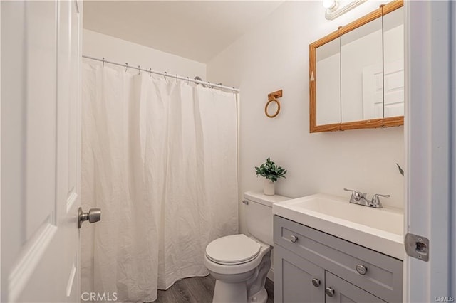 bathroom with toilet, vanity, and wood-type flooring