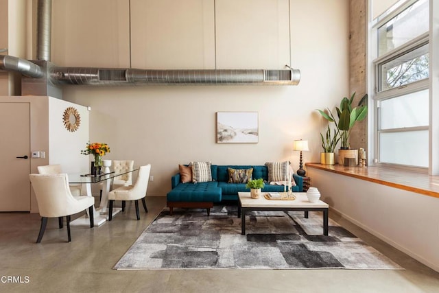 sitting room with concrete flooring and a high ceiling